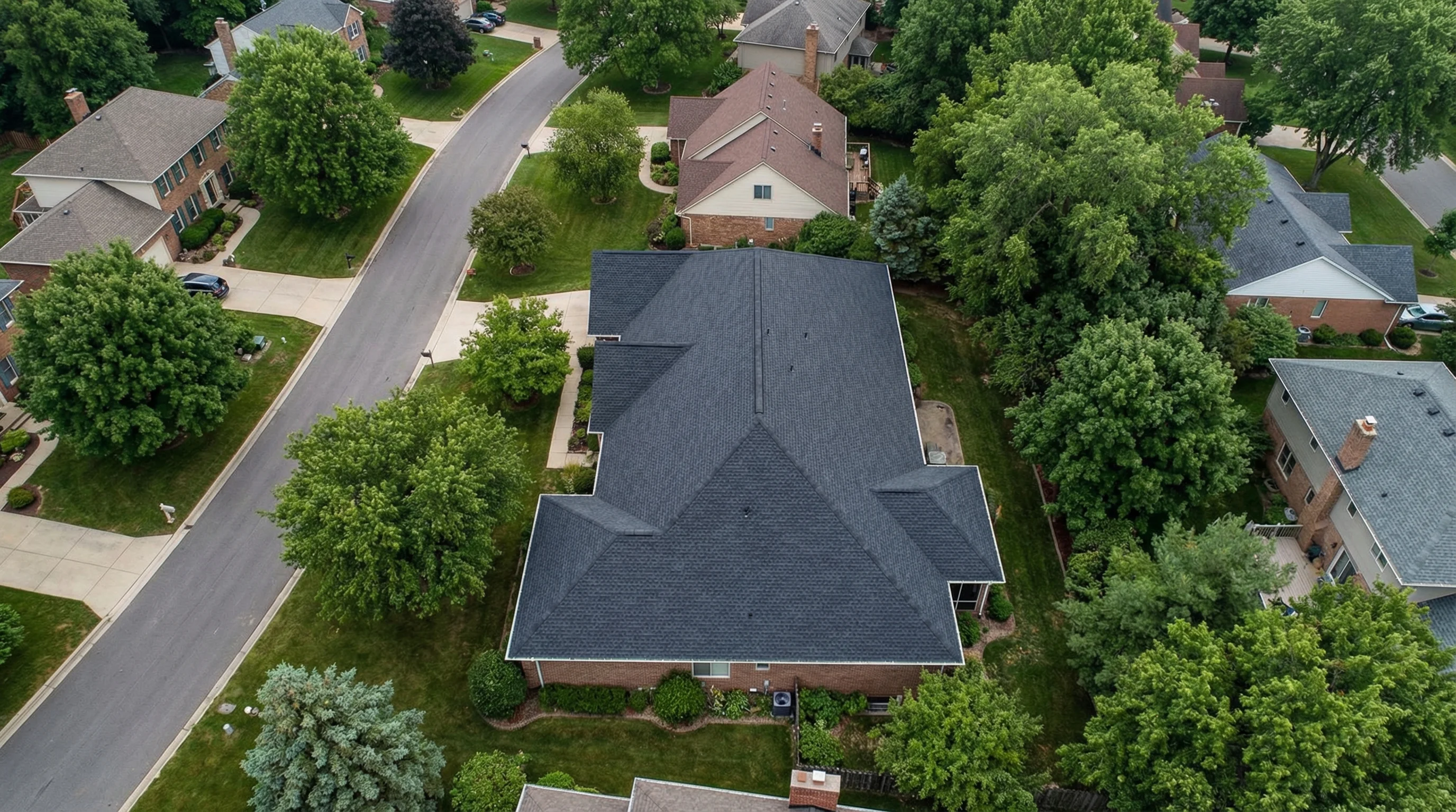 Aerial view of a professionally installed dark charcoal asphalt shingle roof